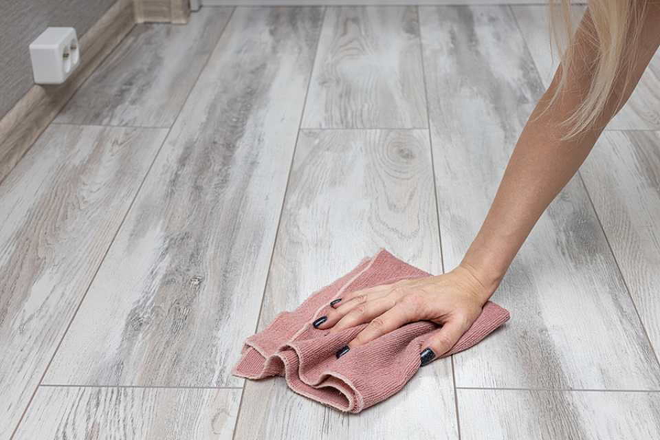 woman cleaning gray look laminate plank